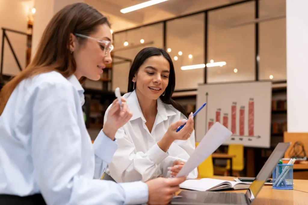 Mulheres analisando relatórios no escritório, simbolizando a produtividade no RH e gestão orientada por dados